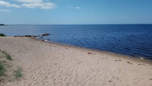 A sandy beach with calm water and a clear sky.