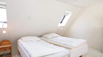 Una habitación pequeña con cama individual, techo inclinado y tragaluz.