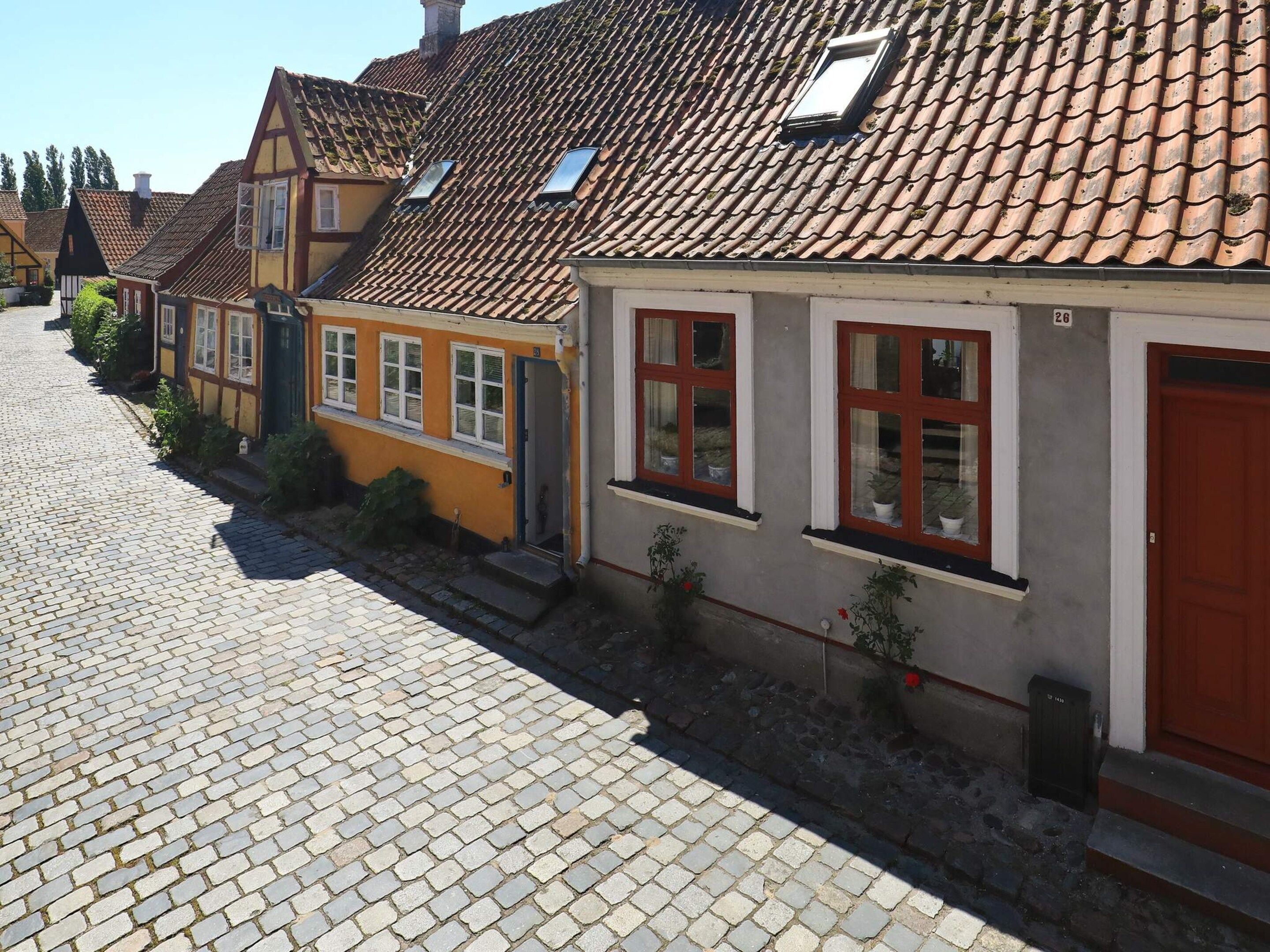 A cobblestone street lined with traditional European-style buildings with pitched roofs and dormer windows.