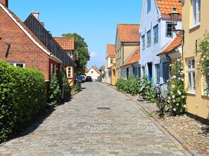 A cobblestone street lined with traditional buildings, a bicycle parked on the right, and a clear blue sky. - 3 Person Holiday Home in Aeroskobing (Aeroskobing)