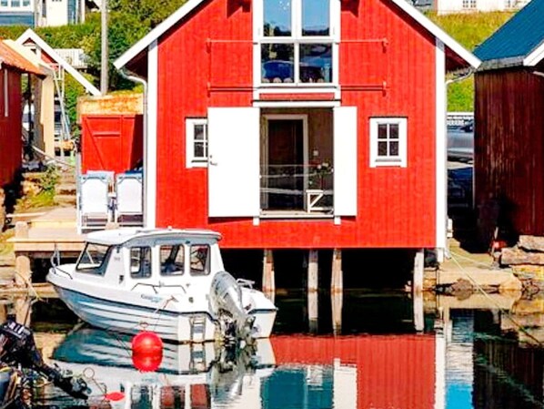 Ein rotes Gebäude mit angedocktem Boot, blauem Himmel und ruhigem Gewässer.