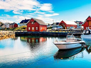 Ein Hafen mit roten Gebäuden, ruhigem Wasser und einem anlegenden Boot.
