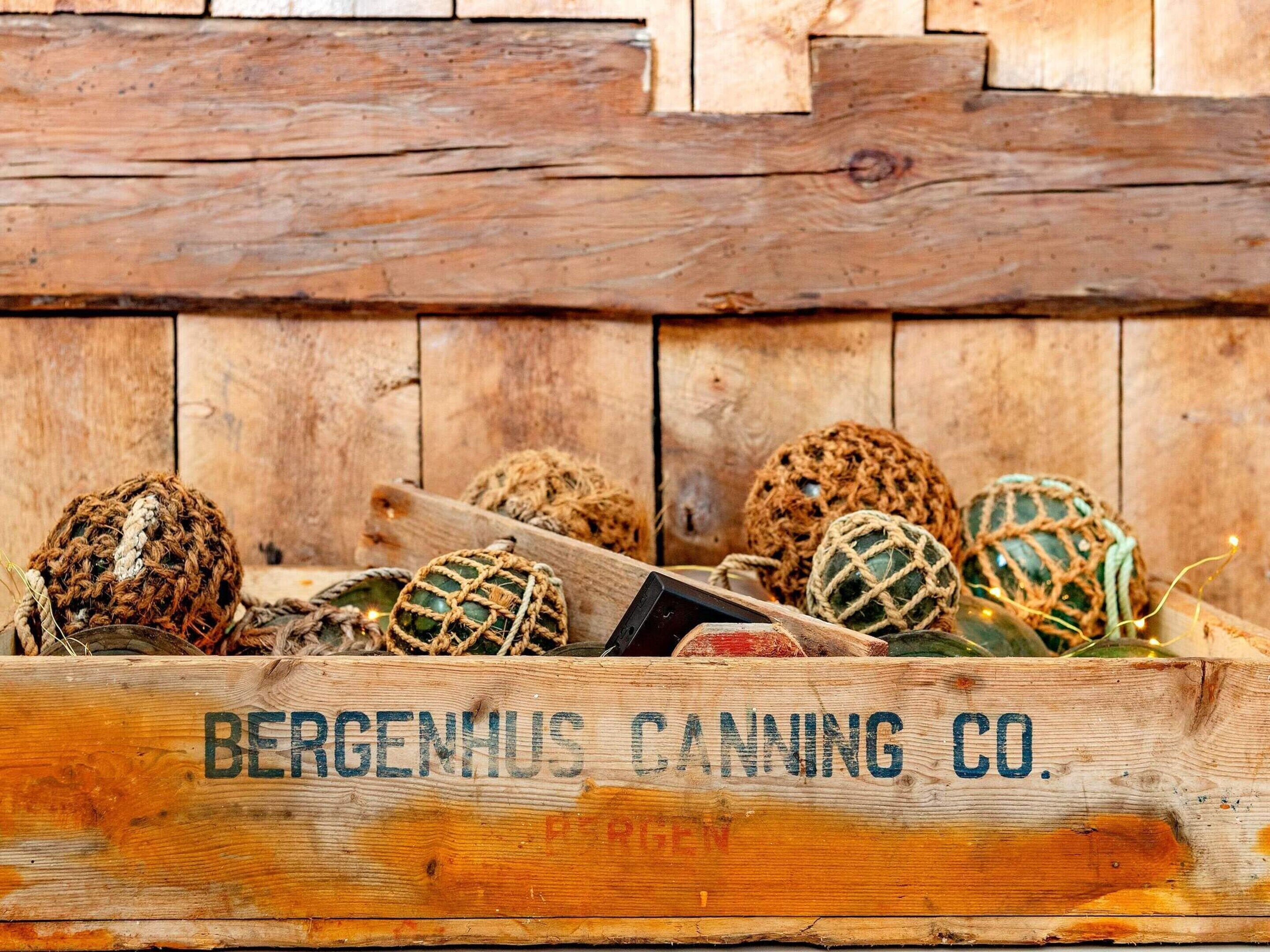 A wooden crate with the text 'BERGENHUS CANNING CO.' and several round, netted objects inside.