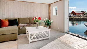Una habitación con pared de madera, un sofá, una mesa de centro blanca y vista a un puerto.