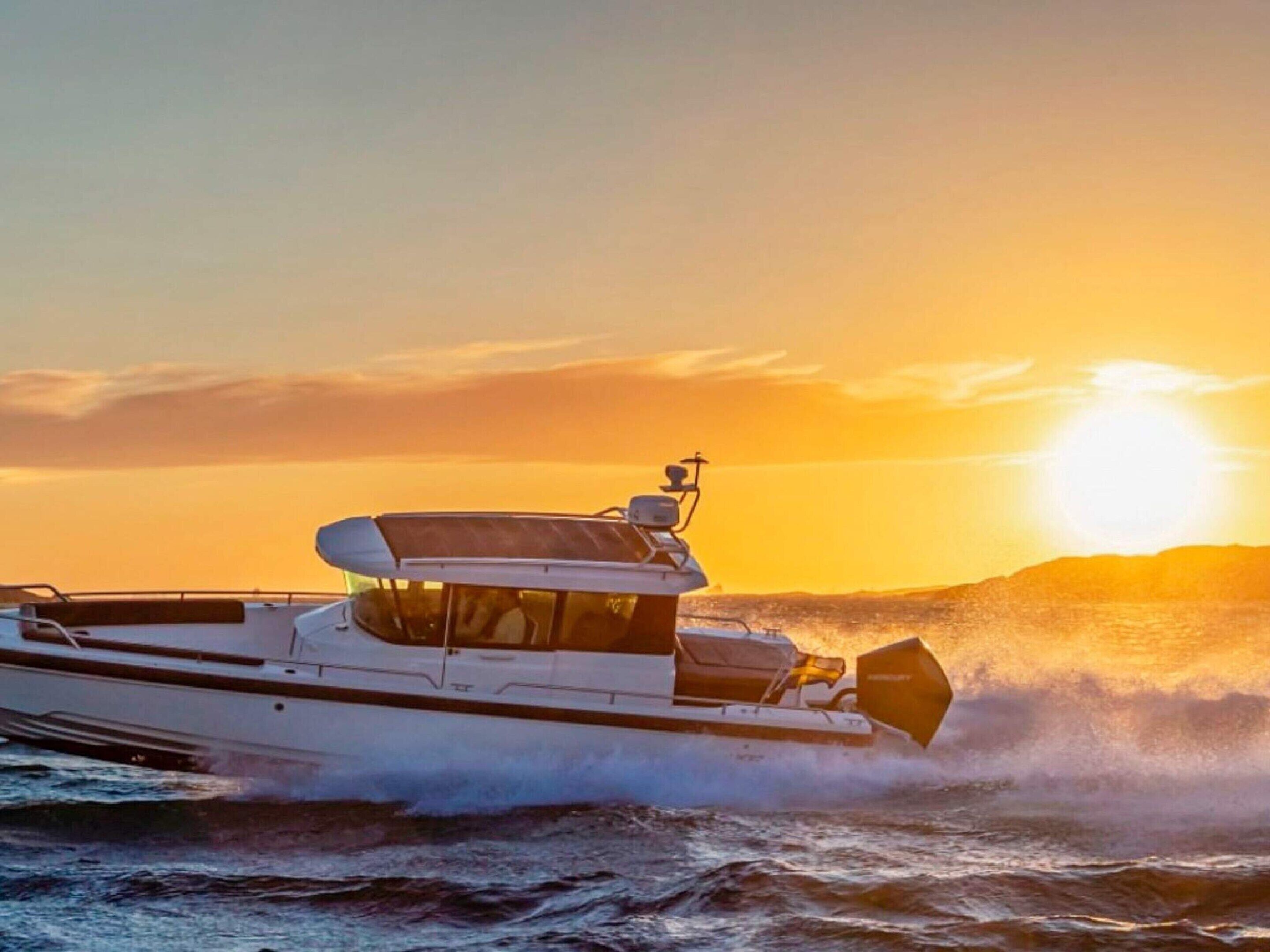 A motorboat on the water with a sun setting in the background.