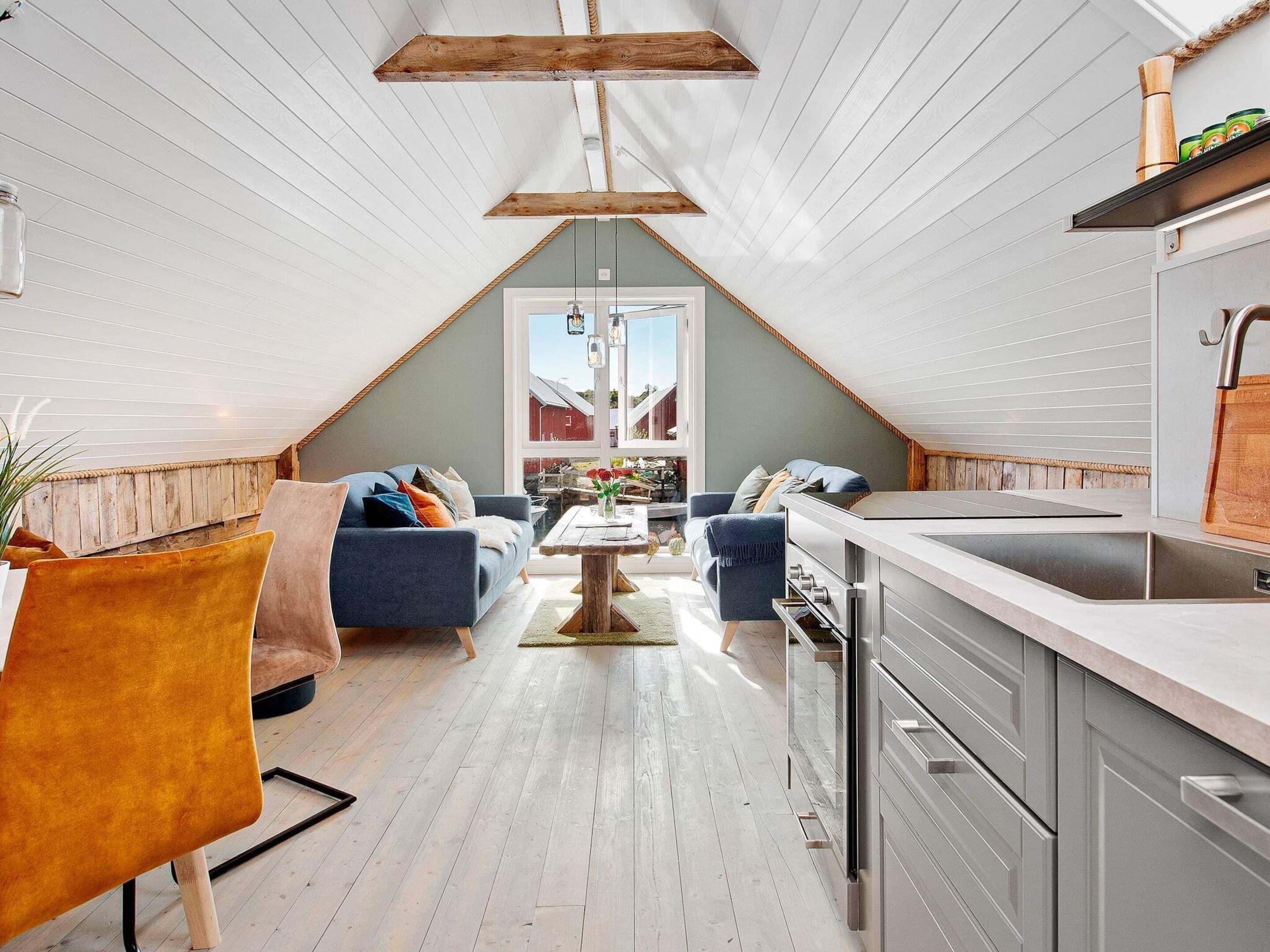 Un espace de vie de style loft comprenant une cuisine, un coin salon et une grande fenêtre.