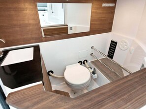 Ein kleines Badezimmer mit Toilette, Spiegel und Duschbereich.