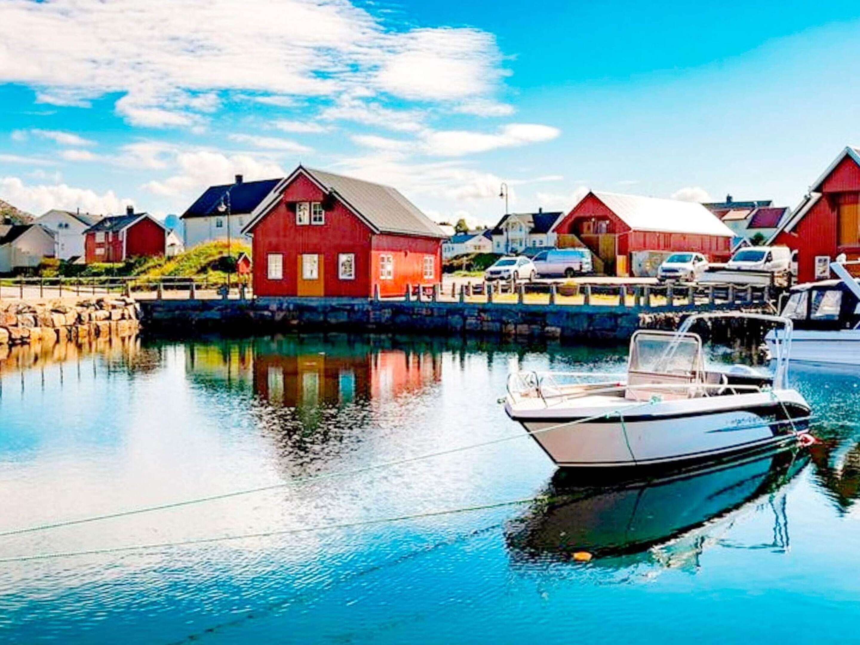A harbor with red buildings, calm water, and a boat docked.