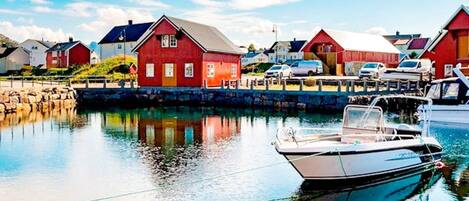 A harbor with red buildings, calm water, and a boat docked.