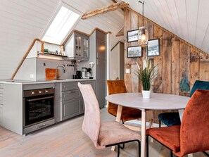 A modern kitchen with a skylight, wooden beams, and a dining area with a round table and velvet chairs. - 5 Star Holiday Home in Bud (Hustadvika)