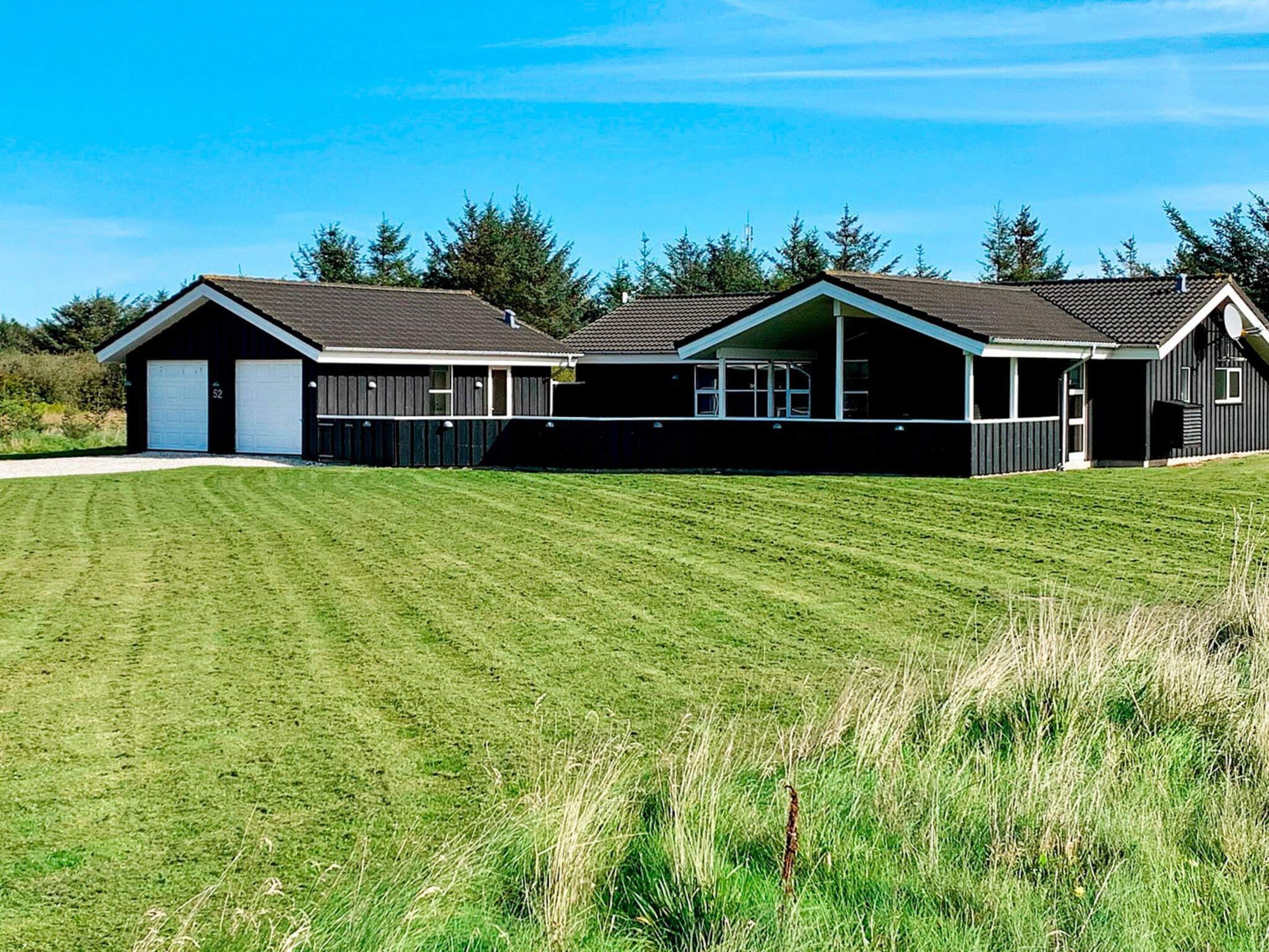 Une maison à deux étages avec un garage, une véranda et une pelouse bien entretenue.