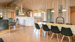 Un intérieur moderne avec un plafond en bois, un îlot central doté de sièges et un coin repas avec une table et des chaises.