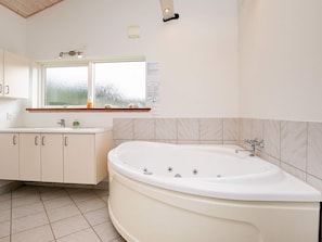 A modern bathroom with a freestanding bathtub, a window, and a countertop with toiletries.