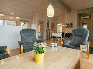 A modern interior with wooden walls, a dining area, and two grey armchairs. - Holiday Home in LÃ¸kken (Lokken)