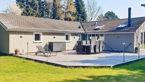 Yhden kerroksen rakennus, jossa on patio, ulkotila istumista varten ja savupiippu.