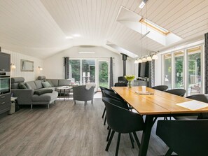 A modern interior with a dining area, sofa set, and a kitchen.