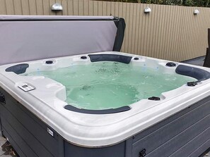 Un bain à remous doté d’un panneau de commande, entouré d’une clôture en bois.
