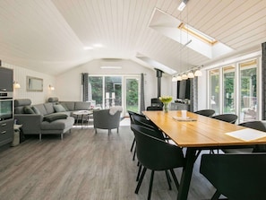 A modern interior with a dining area, sofa set, and a large window providing a view of the outdoors.