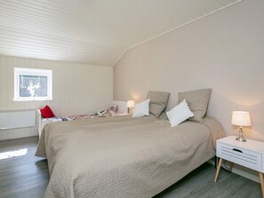 A bedroom with a bed, bedside tables, a window, and a radiator.