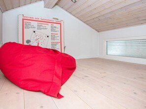 Ein leerer Raum mit einem roten Sitzsack, einem Poster an der Wand und einem Fenster mit Rollläden.