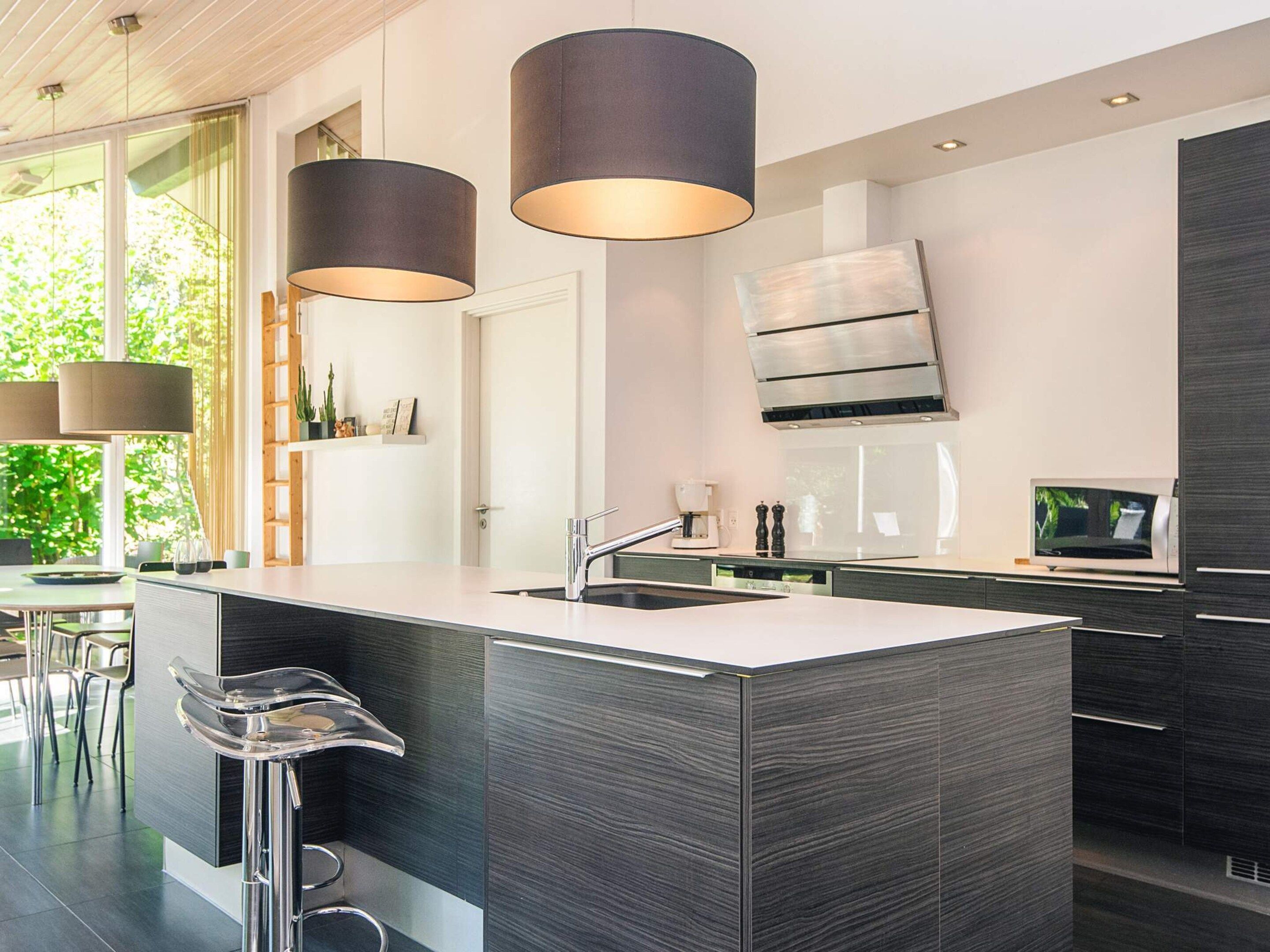 Una cocina moderna con una isla grande, electrodomésticos de acero inoxidable e iluminación colgante.