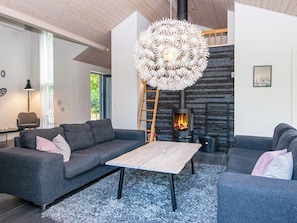 A modern living room with a fireplace, grey sofas, a coffee table, and a unique spherical light fixture. - Holiday Home in Ebeltoft (Ebeltoft)