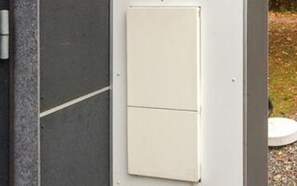 A white electrical box mounted on a wall with a grey surface.