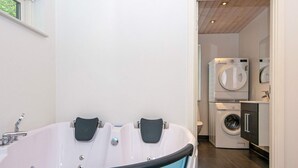 A modern bathroom with a freestanding bathtub, a toilet, and a washing machine.