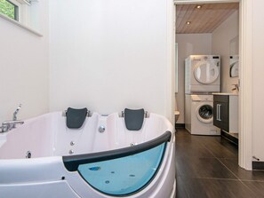 A modern bathroom with a freestanding bathtub, a toilet, and a washing machine.