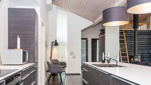 A modern kitchen with dark wood cabinetry, a white countertop, and a built-in stove.