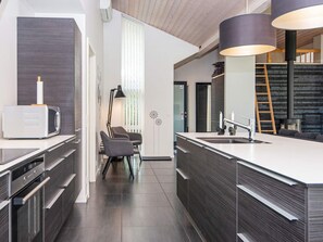A modern kitchen with dark wood cabinetry, a white countertop, and a built-in stove.
