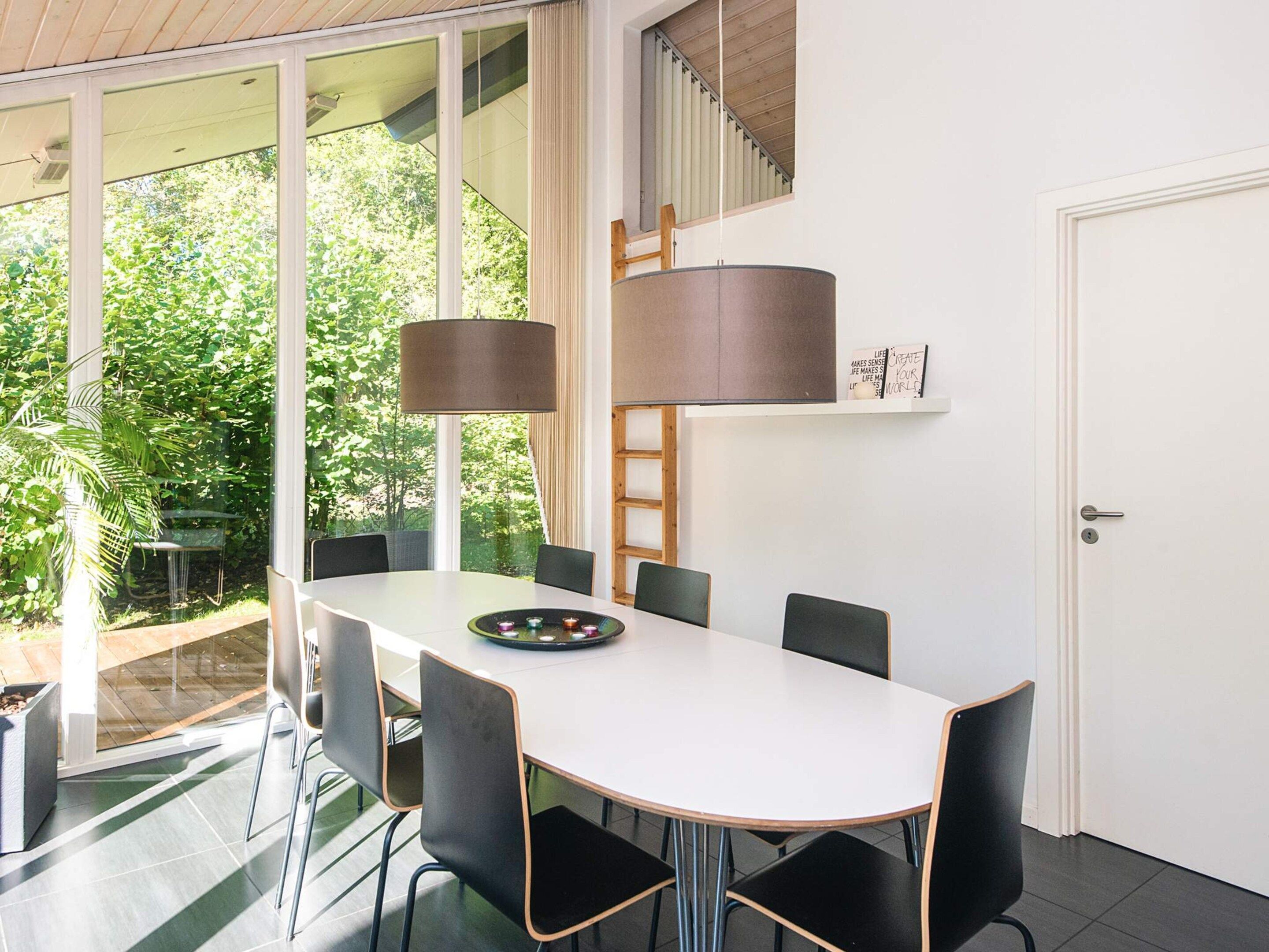A modern dining area with a white table, black chairs, and a large floor lamp.