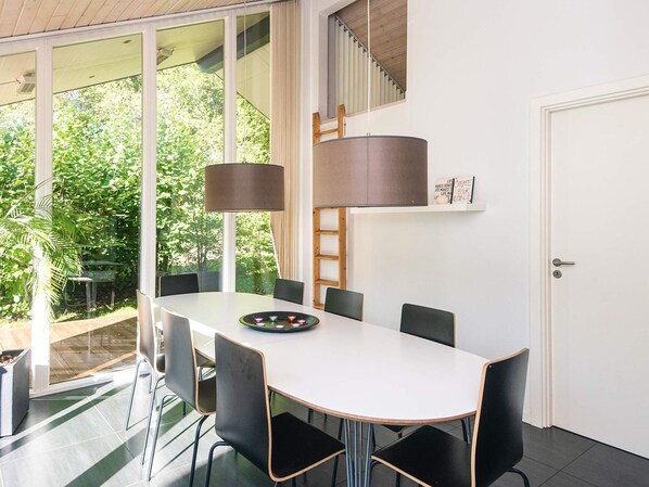 A modern dining area with a white table, black chairs, and a large floor lamp.