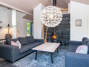 Een moderne woonkamer met een open haard, grijze banken, een salontafel en een opvallende, bolvormige lamp.