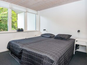 Een slaapkamer met een bed, twee bedlampen, een raam met zonwering, en een kleine plant op de vensterbank.