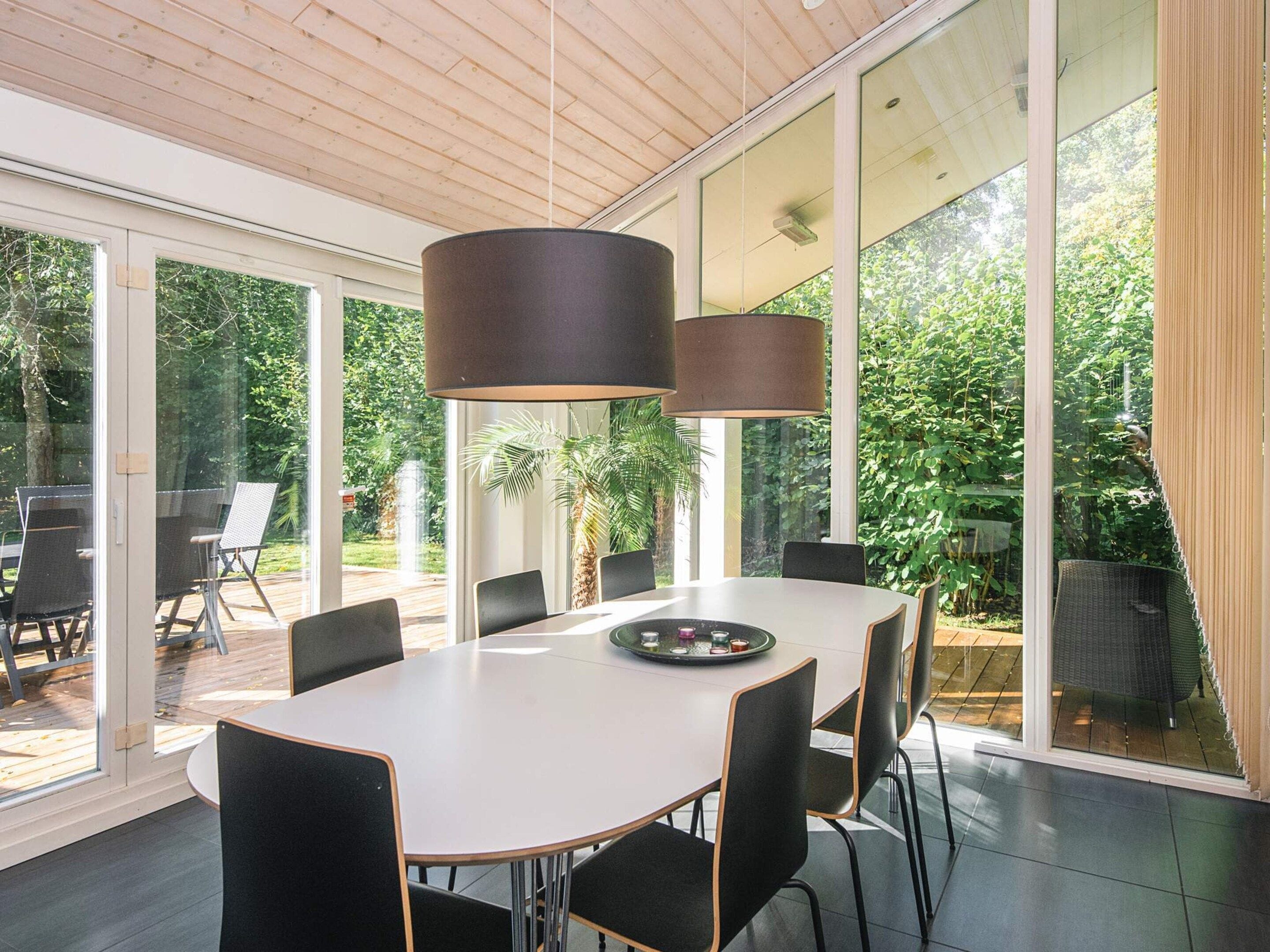 A modern dining area with a large table, chairs, and pendant lights.