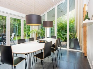 A modern dining area with a large table, black chairs, and pendant lighting.