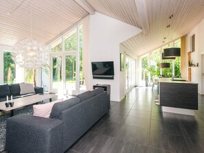 A modern living room with a sectional sofa, a flat-screen TV, and a dining area with a kitchen island.