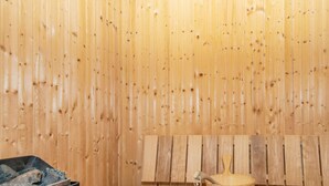 A sauna room with wooden benches and a wooden bucket.