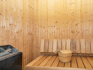 A sauna room with wooden benches and a wooden bucket.