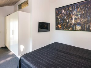A bedroom with a bed, a cityscape painting, and a wardrobe.