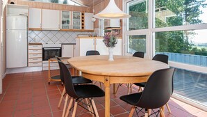 A modern kitchen with a large dining table, black chairs, and a hanging light fixture. - 8 Person Holiday Home in Ebeltoft (Ebeltoft)