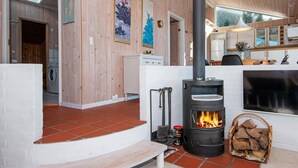 A cozy living room with a wood-burning stove, a bench, and a fireplace. - 8 Person Holiday Home in Ebeltoft (Ebeltoft)