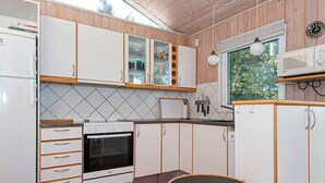 A compact kitchen with white cabinets, a stove, and a small round table. - 8 Person Holiday Home in Ebeltoft (Ebeltoft)