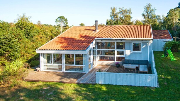 A two-story house with a wooden deck and a covered porch. - 8 Person Holiday Home in Ebeltoft (Ebeltoft)