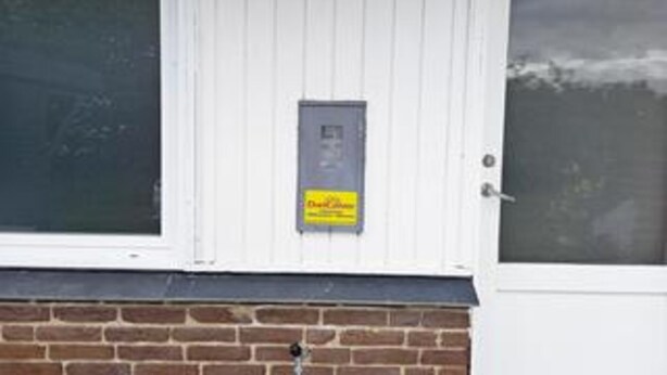 Eine weiße Tür mit einem kleinen Schild und einem Fenster mit Blick zum Himmel.