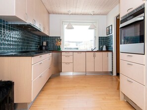 A modern kitchen with wooden cabinets, a black countertop, and a built-in oven.