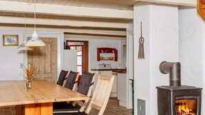 A cozy dining area with a wooden table and chairs, a pendant light, and a wood-burning stove. - Cozy Coastal Cottage at Jegindo-by Traum (Thyholm)