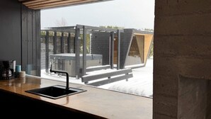 Una cocina moderna con ventanal a una terraza de madera y un jacuzzi.