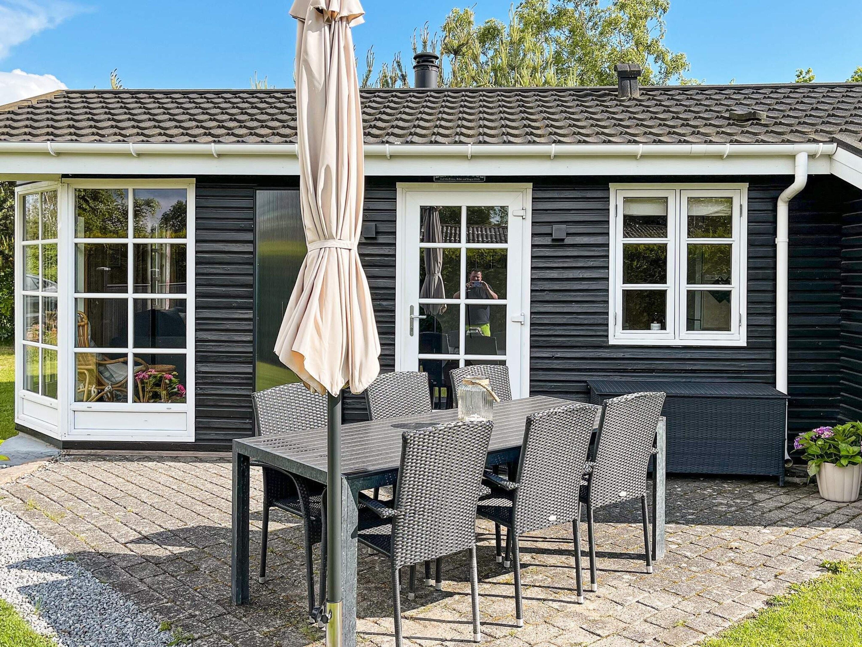 A house with a patio, a table with chairs, and a covered umbrella.